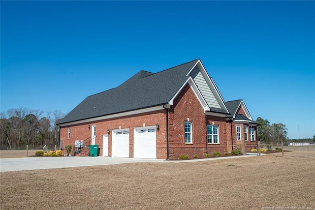 view of side of home with brick siding, driveway, and a garage