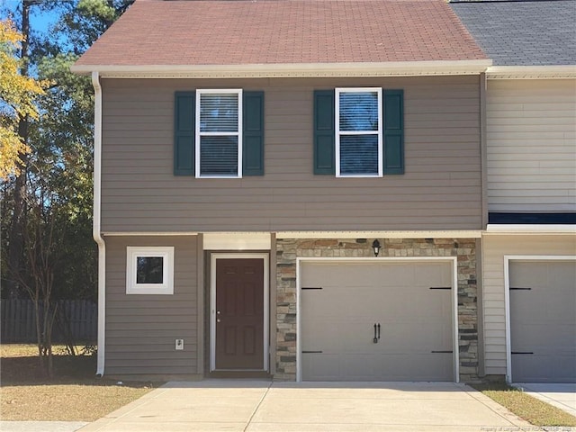 townhome / multi-family property featuring a garage, stone siding, roof with shingles, and driveway