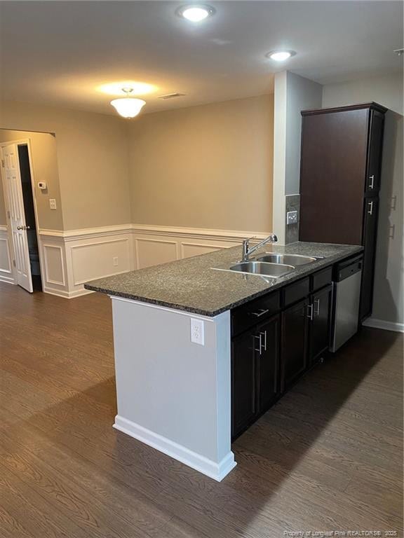 kitchen with a sink, dark wood-style floors, dark stone counters, a peninsula, and dishwasher