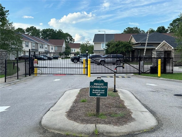 view of street featuring curbs, a gate, a gated entry, a residential view, and sidewalks