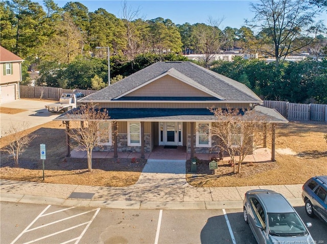 view of front of property with a porch, fence, and roof with shingles