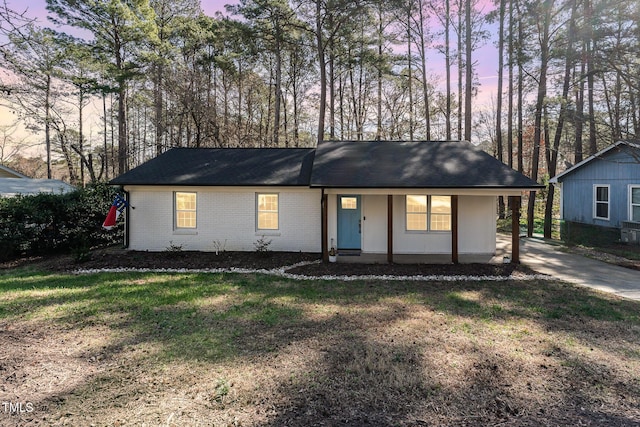 ranch-style house with brick siding, a lawn, and a carport