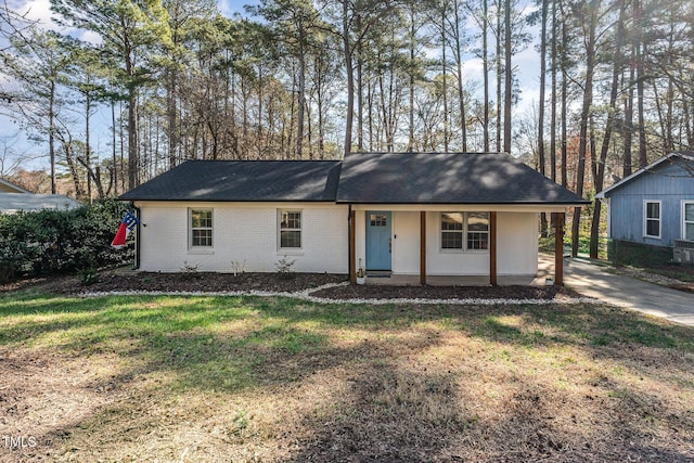 ranch-style home with an attached carport, roof with shingles, driveway, a front lawn, and brick siding