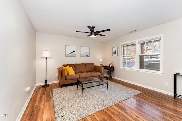 living area featuring wood finished floors, a ceiling fan, visible vents, and baseboards