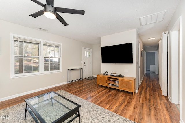 living room featuring visible vents, ceiling fan, baseboards, and wood finished floors