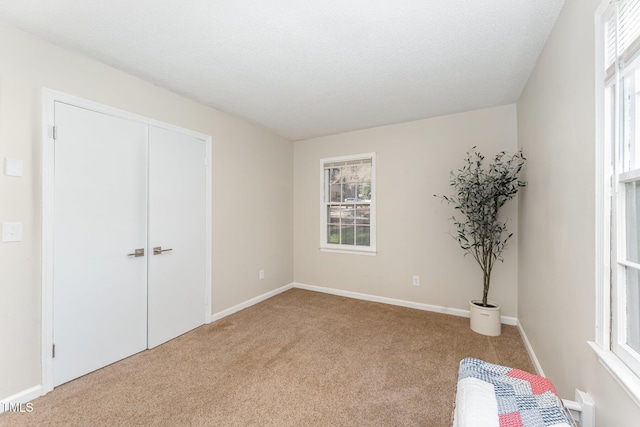 carpeted bedroom featuring multiple windows, baseboards, and a textured ceiling