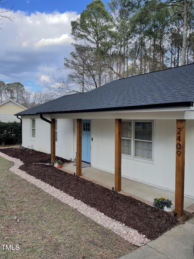 single story home featuring brick siding and a shingled roof