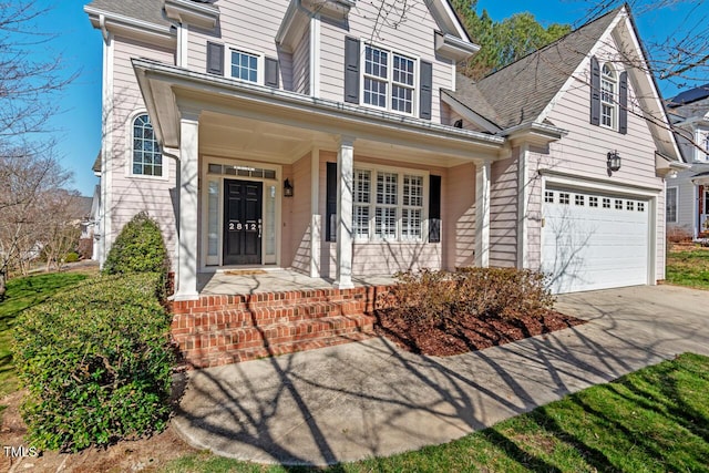 view of front of home featuring covered porch, an attached garage, concrete driveway, and roof with shingles