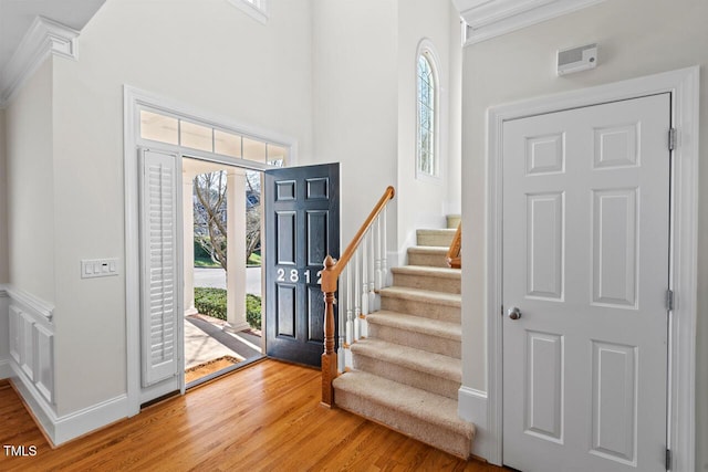 entryway with stairway, baseboards, crown molding, and light wood finished floors