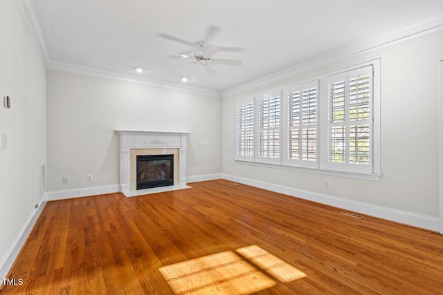 unfurnished living room featuring wood finished floors, visible vents, a ceiling fan, baseboards, and ornamental molding