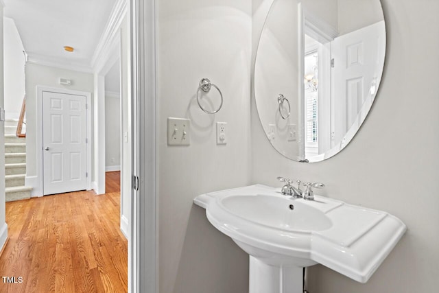 bathroom with wood finished floors, baseboards, and ornamental molding