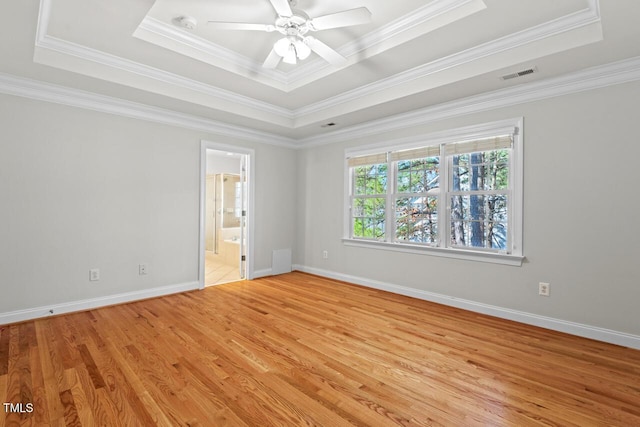 unfurnished room with a raised ceiling, baseboards, visible vents, and light wood-type flooring