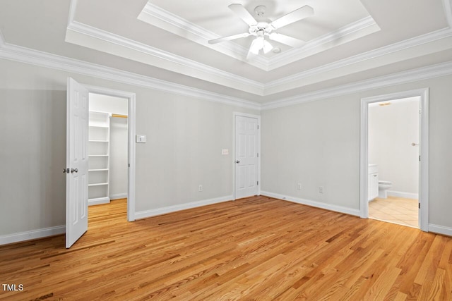 unfurnished bedroom with baseboards, a raised ceiling, and light wood-style floors