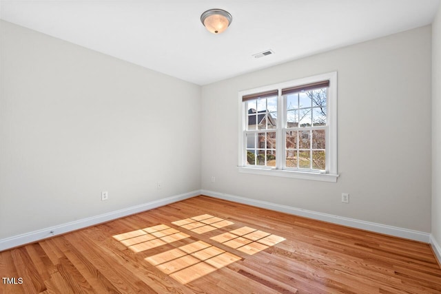 spare room with visible vents, baseboards, and wood finished floors