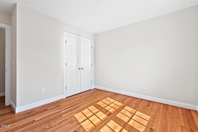 unfurnished bedroom featuring a closet, baseboards, and light wood-style floors