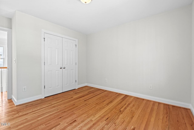 unfurnished bedroom featuring a closet, baseboards, and light wood finished floors