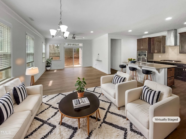 living room with baseboards, light wood finished floors, an inviting chandelier, recessed lighting, and ornamental molding