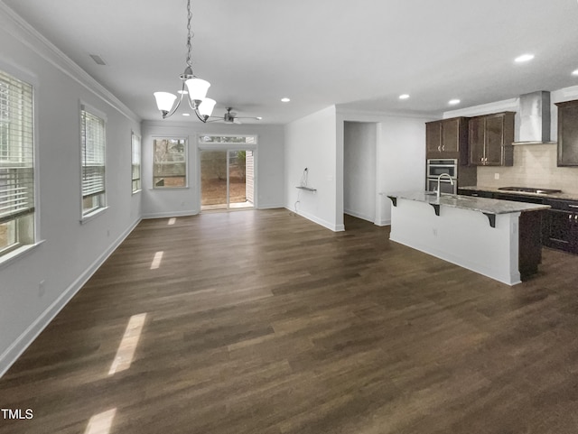 kitchen with gas cooktop, a breakfast bar area, wall chimney exhaust hood, crown molding, and dark brown cabinets