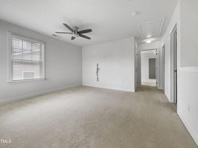 unfurnished room featuring attic access, light colored carpet, baseboards, and ceiling fan