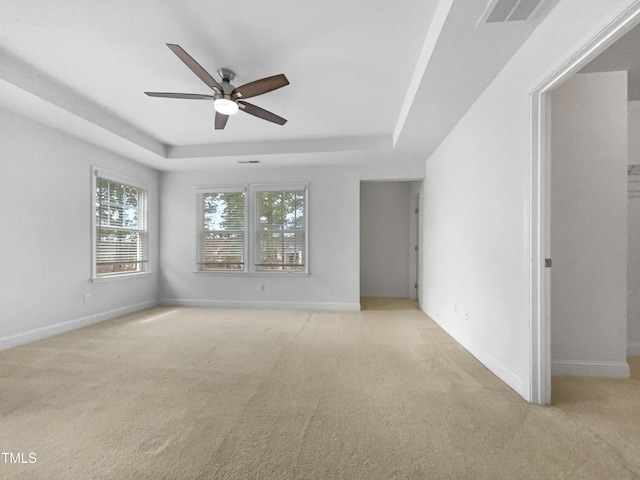 unfurnished room featuring a raised ceiling, baseboards, visible vents, and light carpet