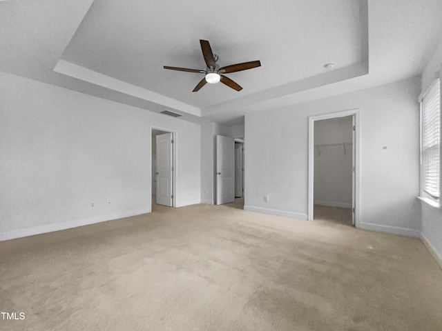 unfurnished bedroom with visible vents, ceiling fan, baseboards, light carpet, and a raised ceiling