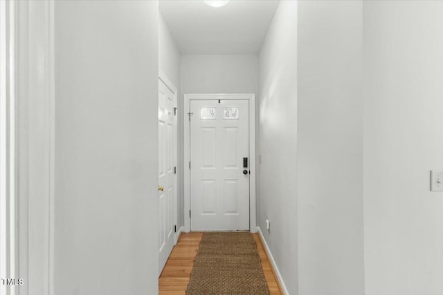 hall with baseboards and light wood finished floors