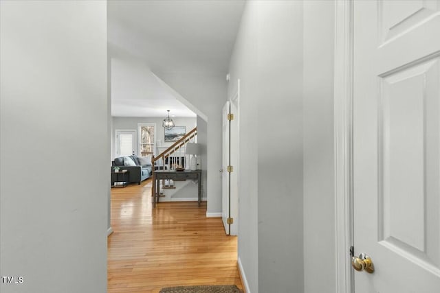 hall featuring stairway, light wood-type flooring, and baseboards