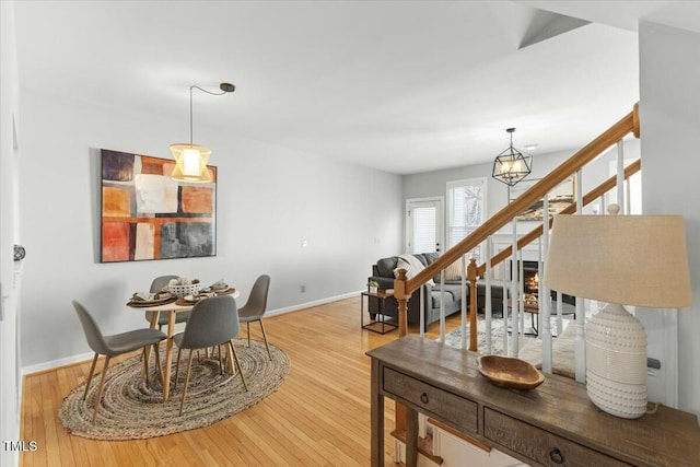 dining area featuring baseboards, a notable chandelier, stairs, and hardwood / wood-style flooring