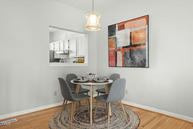 dining room featuring visible vents, wood finished floors, and baseboards