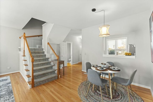 dining space featuring stairway, light wood-style flooring, and baseboards