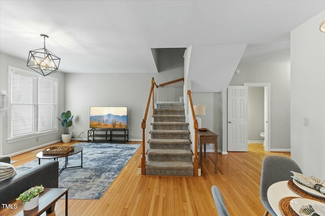 living room with a notable chandelier, stairs, baseboards, and wood finished floors