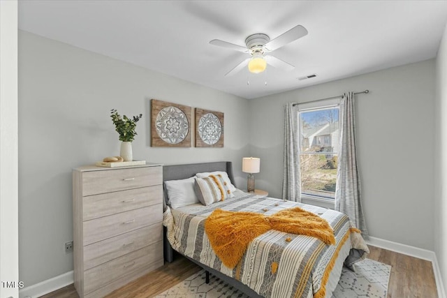 bedroom with visible vents, a ceiling fan, baseboards, and wood finished floors