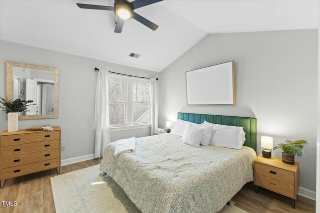 bedroom with a ceiling fan, wood finished floors, baseboards, visible vents, and vaulted ceiling