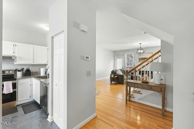 kitchen featuring a sink, light wood-style flooring, white cabinetry, and stainless steel appliances