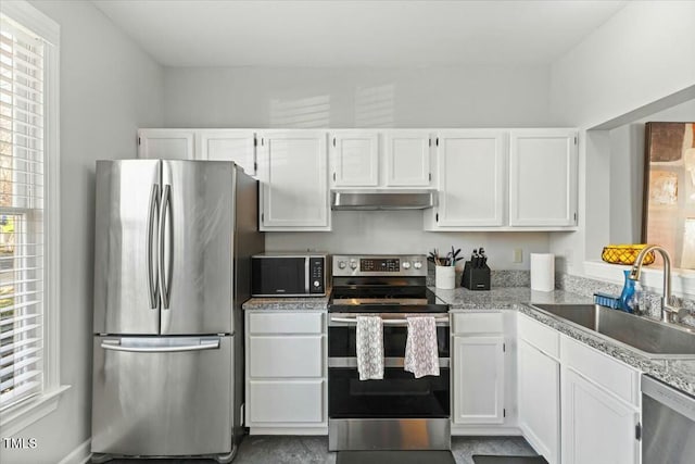 kitchen featuring a sink, wall chimney range hood, stainless steel appliances, white cabinets, and light countertops