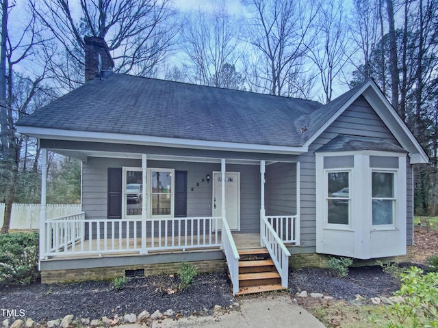 view of front of property featuring fence, a porch, roof with shingles, a chimney, and crawl space