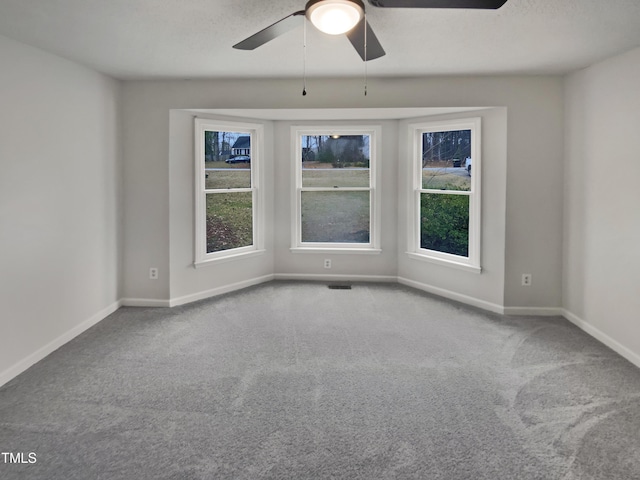 carpeted spare room featuring visible vents, baseboards, and ceiling fan