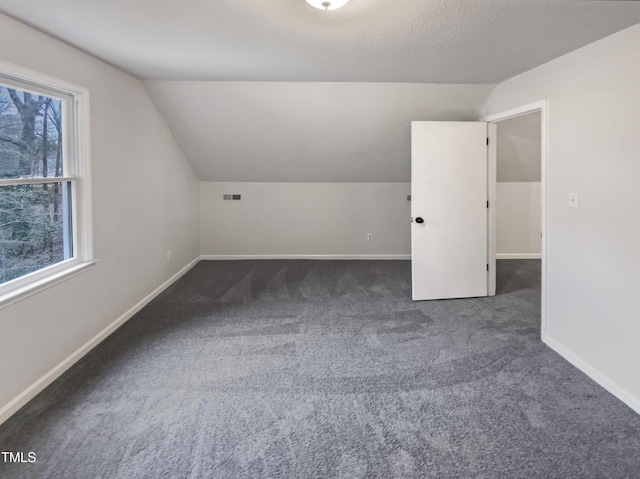 bonus room featuring baseboards, a textured ceiling, carpet floors, and vaulted ceiling