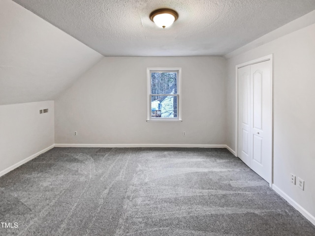 bonus room featuring visible vents, a textured ceiling, carpet flooring, and vaulted ceiling