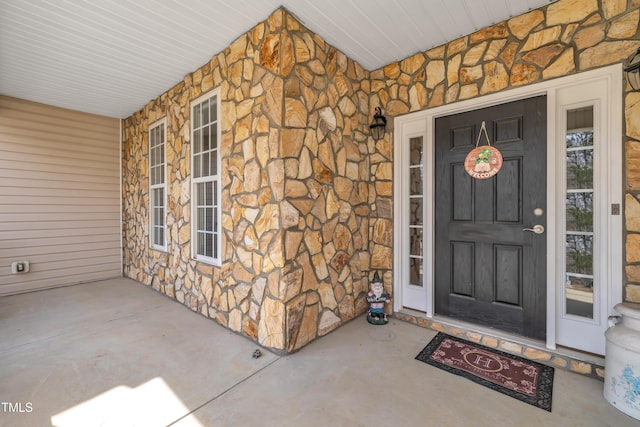 doorway to property with stone siding and covered porch