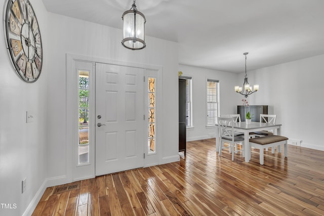 entryway featuring a notable chandelier, wood finished floors, visible vents, and baseboards