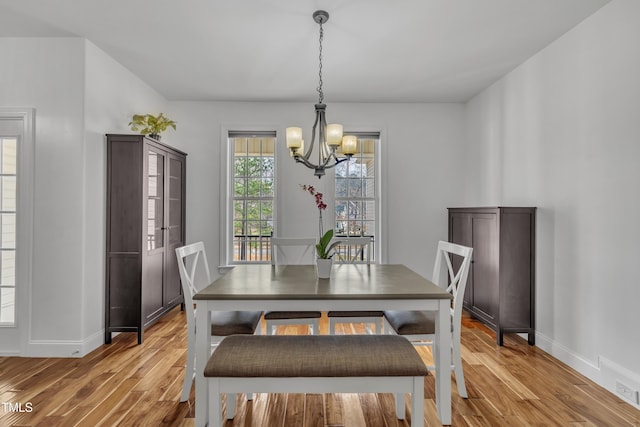 dining area featuring baseboards, light wood-style floors, and an inviting chandelier