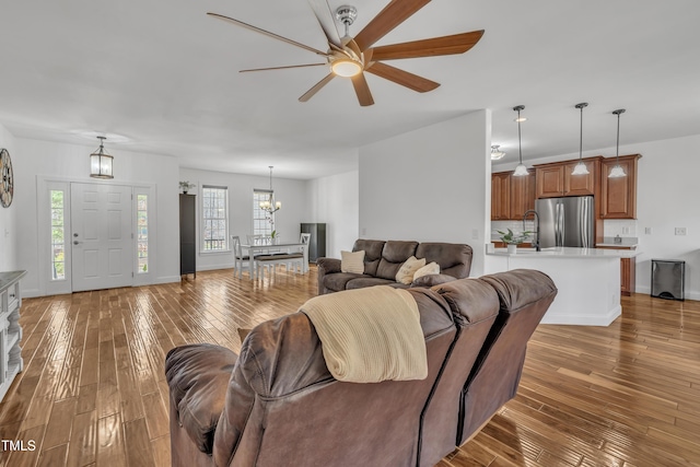 living room with baseboards, wood-type flooring, and ceiling fan with notable chandelier