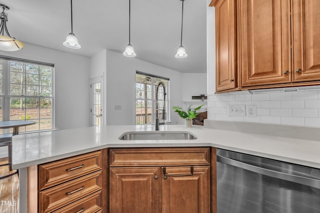 kitchen featuring a sink, a healthy amount of sunlight, light countertops, and stainless steel dishwasher