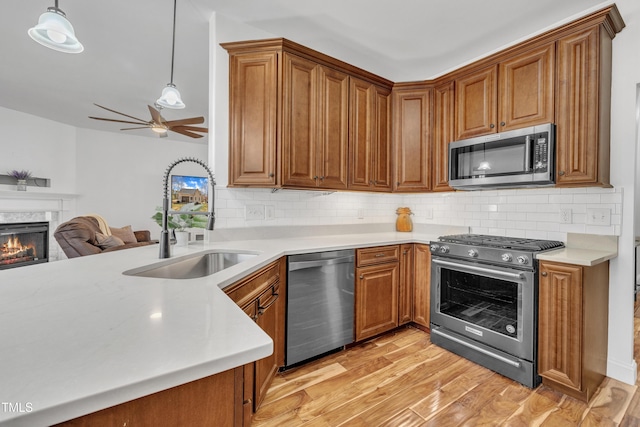 kitchen featuring a ceiling fan, brown cabinets, appliances with stainless steel finishes, and a sink