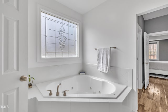 ensuite bathroom with a jetted tub, ensuite bath, and wood finished floors