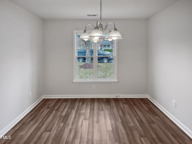 interior space with dark wood finished floors, a notable chandelier, and baseboards