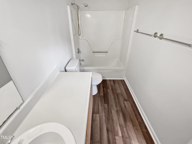 full bathroom featuring wood finished floors, baseboards, a sink, shower / washtub combination, and toilet