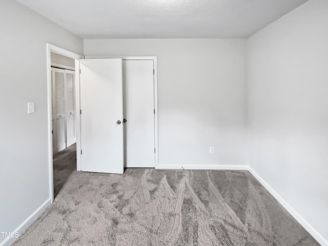 unfurnished bedroom with carpet, baseboards, and a closet