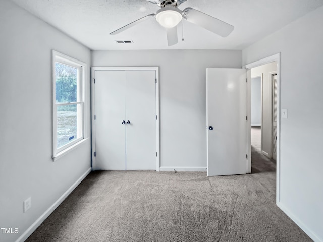 unfurnished bedroom featuring carpet, visible vents, a closet, and baseboards